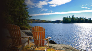 View of the lake on a sunny day with two reclining chairs waiting for you.