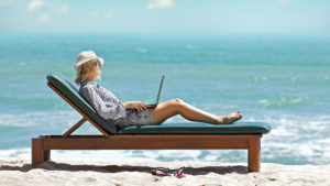 Woman on a beach with a laptop